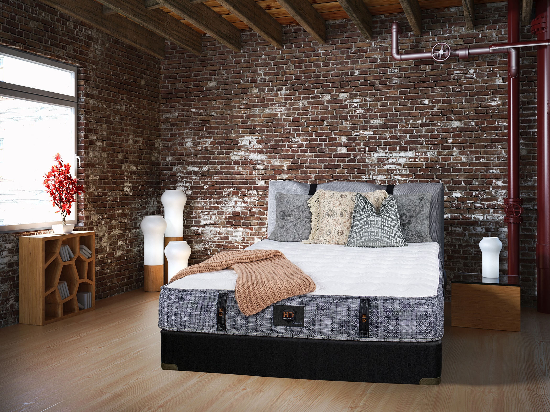 Photo of a bedroom with mattress and throw pillows against an exposed brick wall and modern decor