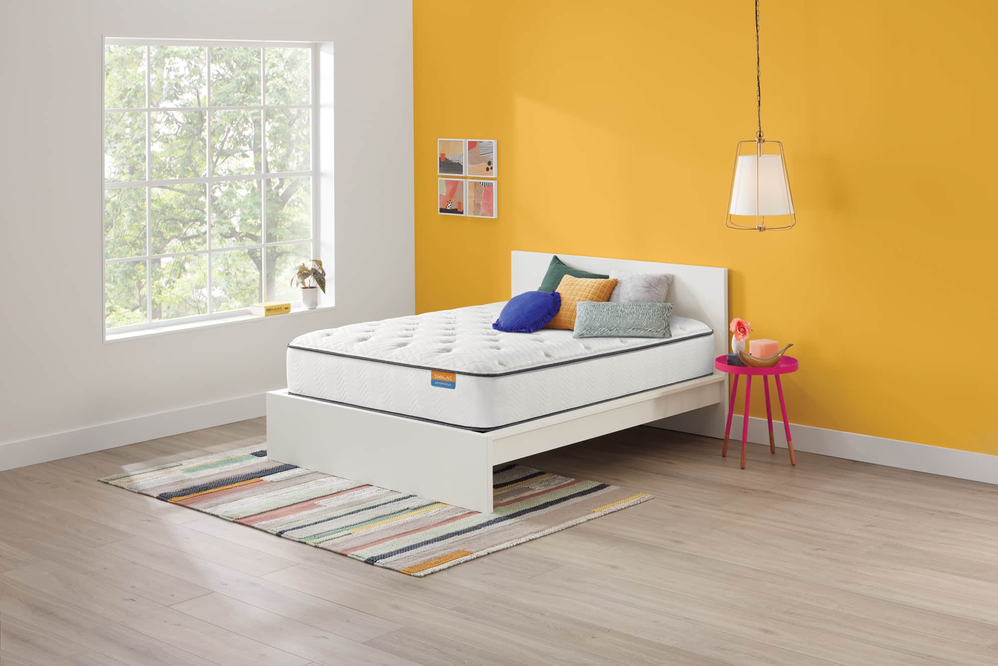 White Simmons mattress and frame in a yellow room with rug